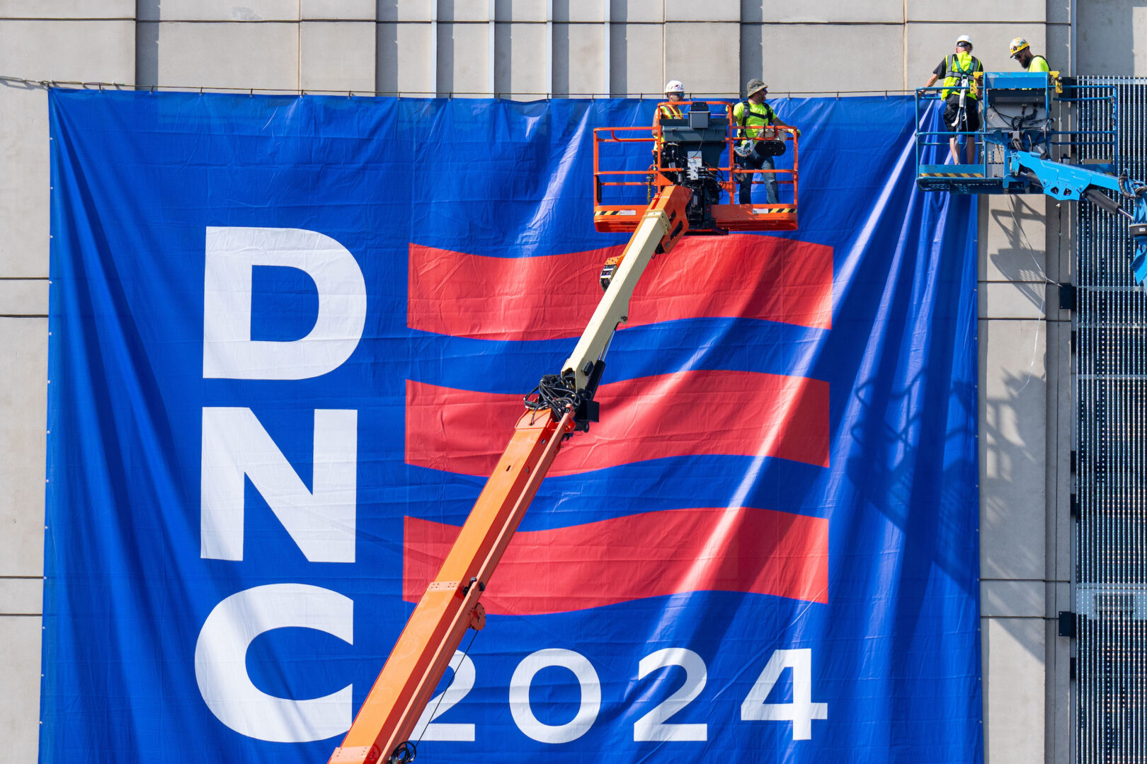 Workers install a 2024 DNC banner to the exterior of the United Center in Chicago on August 14 as the city gears up for the for the Democratic National Convention.