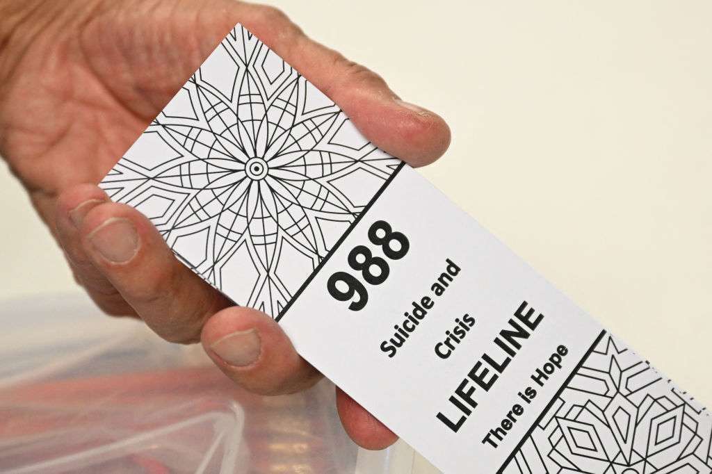 A bookmark for children with the 988 suicide and crisis lifeline emergency telephone number is displayed by a volunteer with the Natrona County Suicide Prevention Task Force while speaking  about mental health and suicide awareness in Casper, Wyo. on Aug. 14, 2022.