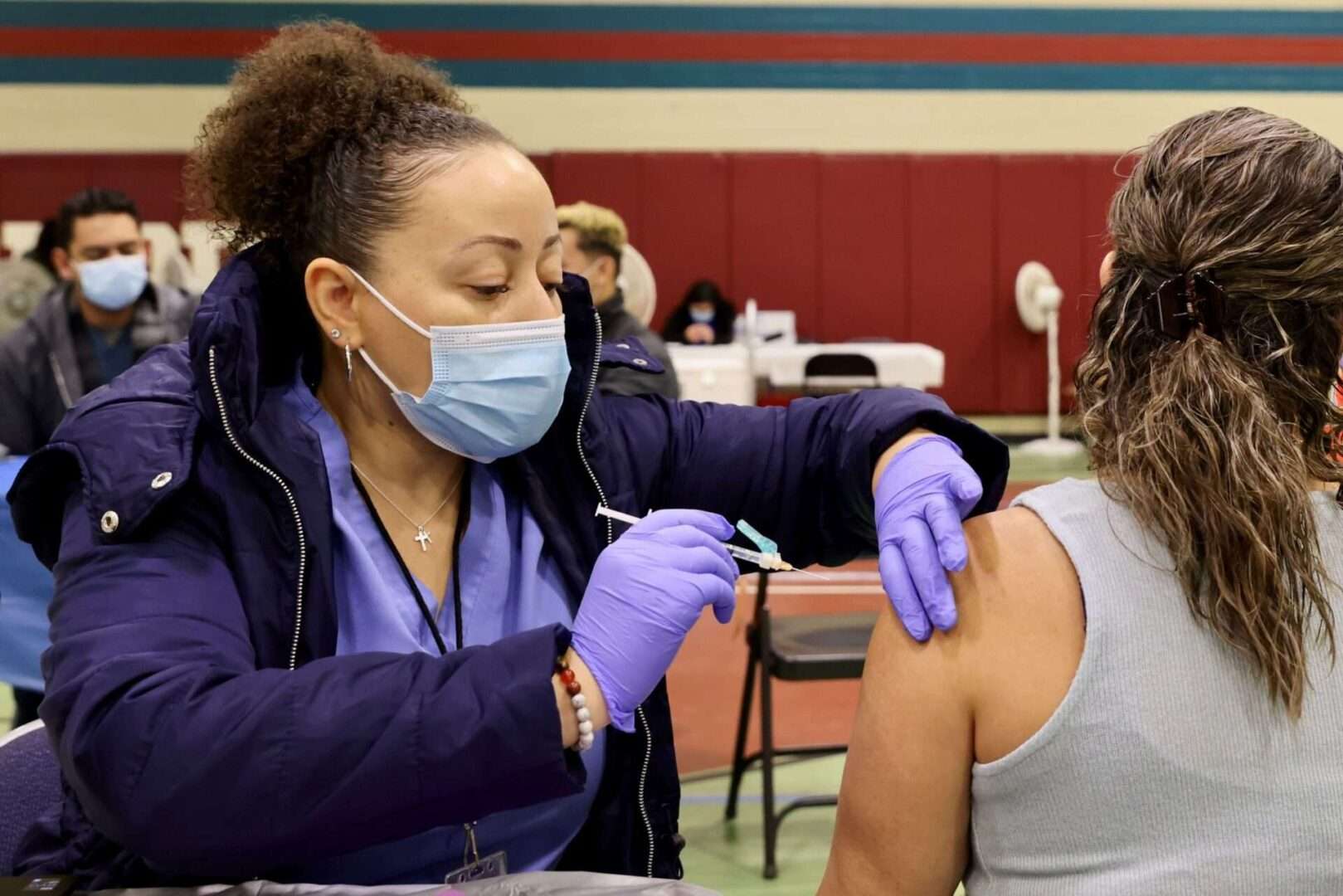 A health worker administers a COVID-19 vaccine shot to a local resident in Los Angeles on Dec. 17, 2022. Critics worry that the Centers for Disease Control and Prevention's new program to get the next generation of COVID-19 vaccines to uninsured and underinsured Americans will likely not be ready in pharmacies by the time the new vaccines hit the market as early as this September.