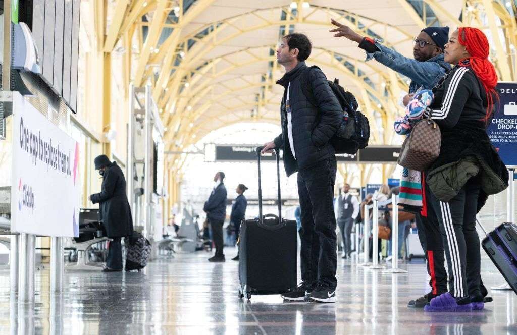 Travelers look at a flight information display listing canceled and delayed flights due to an FAA outage that grounded flights across the US at Ronald Reagan Washington National Airport on Wednesday.