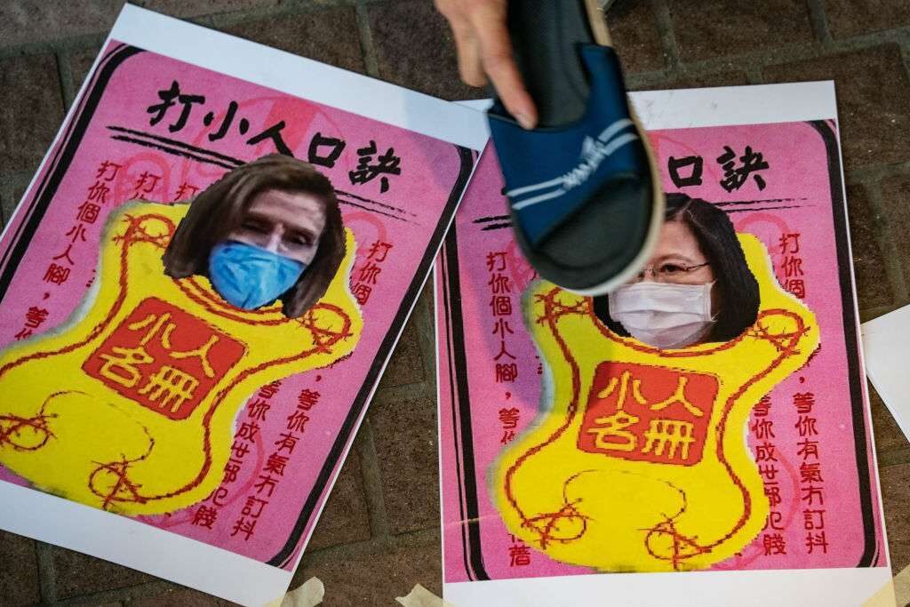 A pro-China supporter hits images of Speaker Nancy Pelosi, D-Calif., and Taiwanese President Tsai Ing-wen with a shoe, during a rally on Aug. 11.