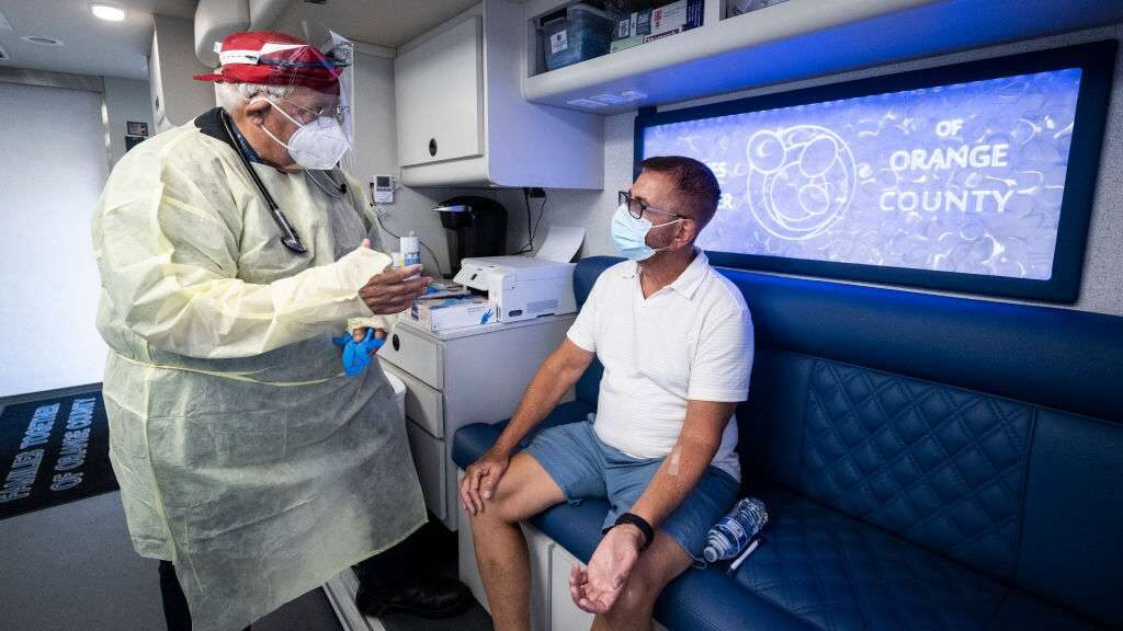 A physician assistant talks with a man after he received the monkeypox vaccine at Families Together of Orange County in Tustin, Calif., in August. The Jynneos vaccine consists of two doses administered 28 days apart. 