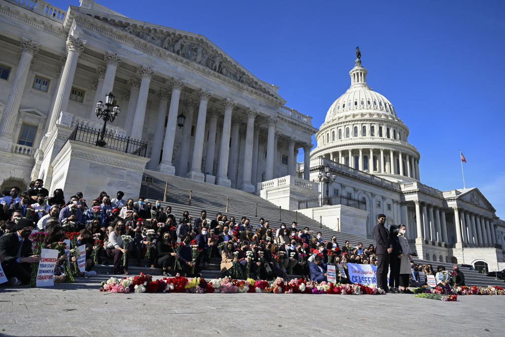 Congressional aides gather on the House steps on Nov. 8 as they unfurl a banner demanding a cease-fire. Now staffers have organized a fundraiser for humanitarian aid. 