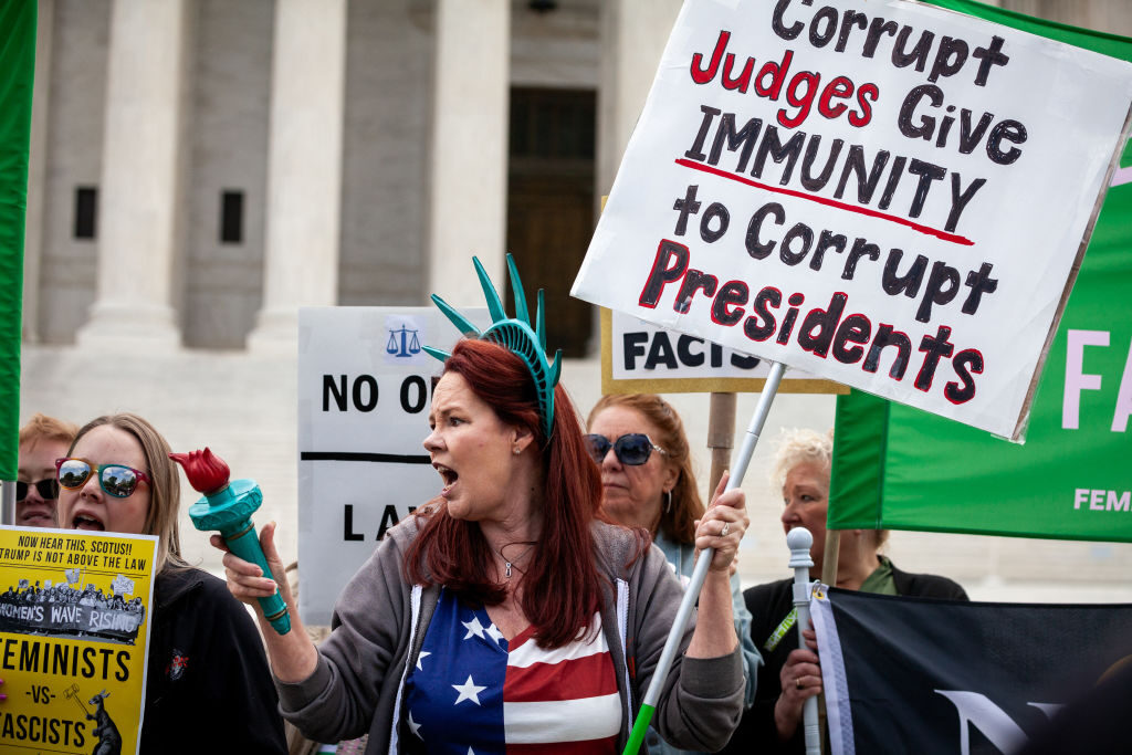 People demonstrate against former President Donald Trump on Thursday while the Supreme Court hears oral arguments on his claim of immunity from prosecution.