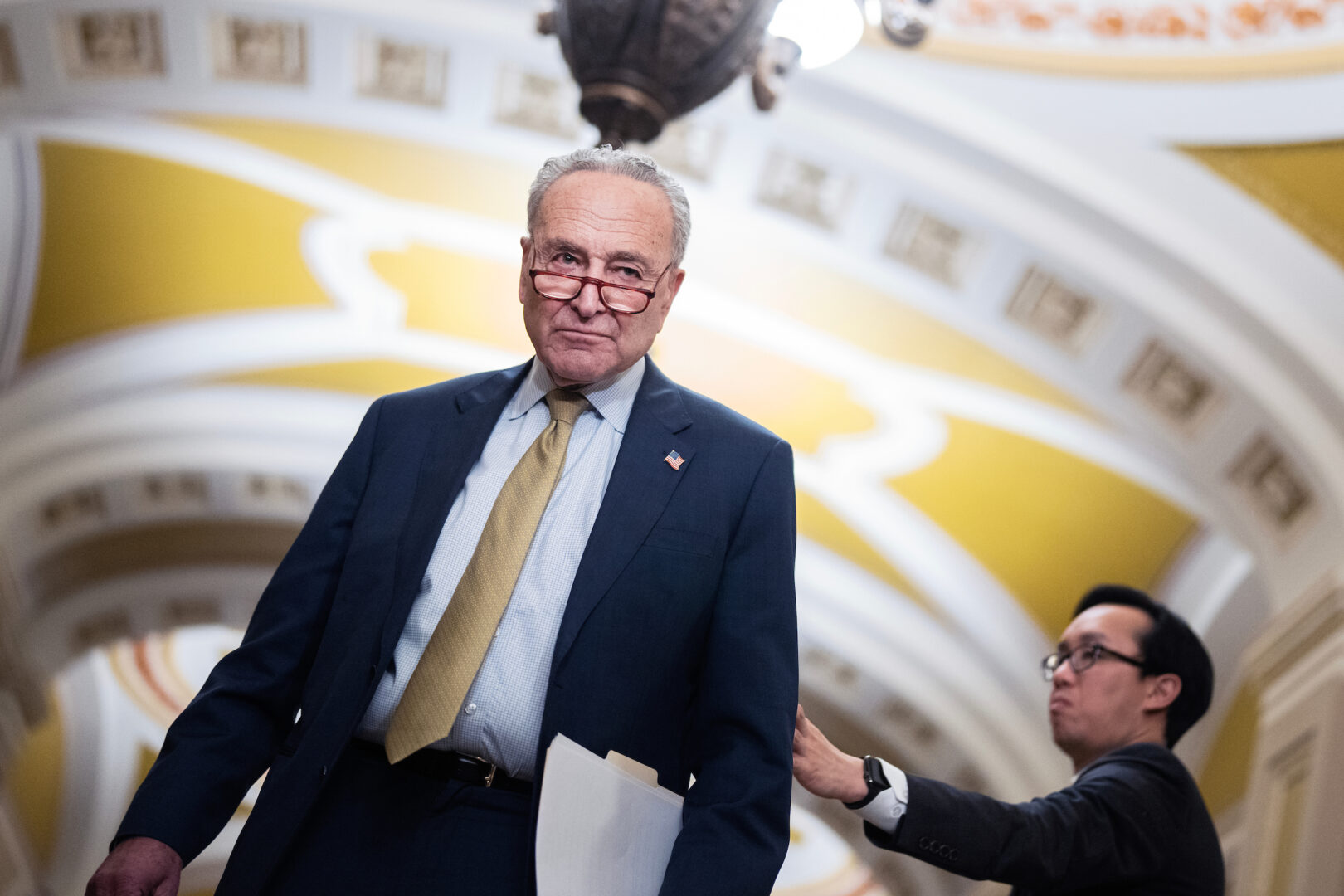 Senate Majority Leader Charles E. Schumer, D-N.Y., and aide Alex Nguyen attend a news conference after the Senate luncheons in the Capitol on Tuesday.