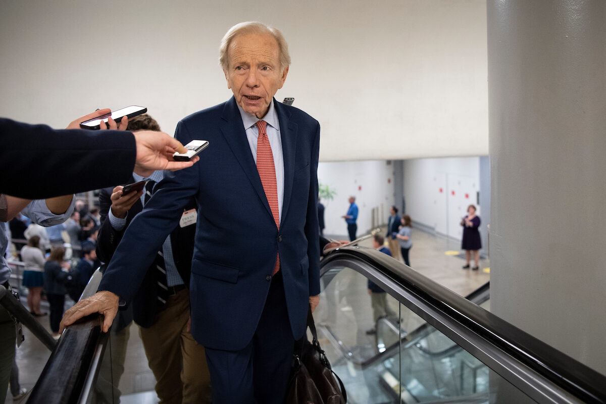 Former Sen. Joseph I. Lieberman talks with reporters as he walks through the Senate subway in Washington on June 22, 2021. 