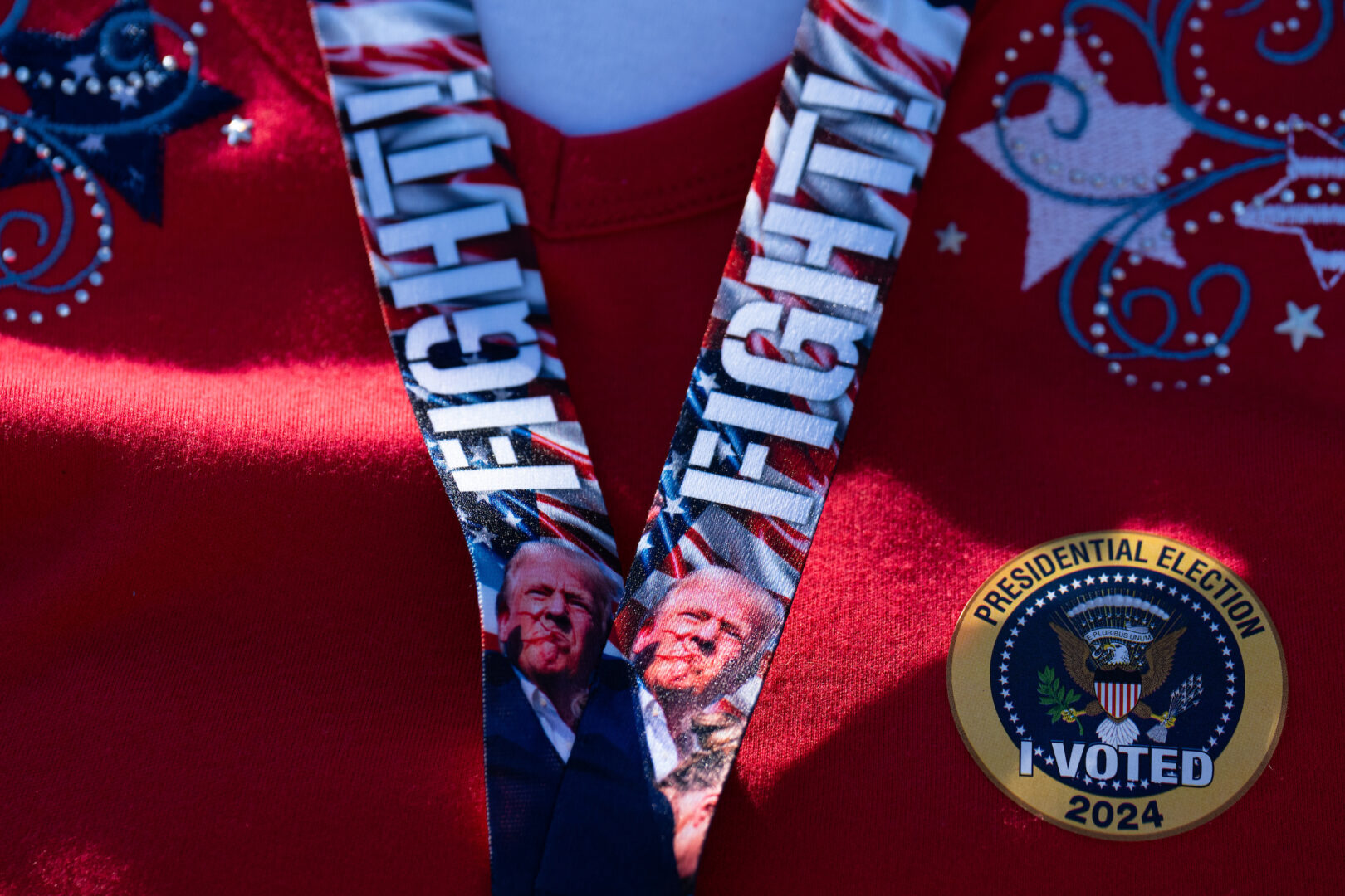 A Republican voter Friday in Orange, Va., wears a lanyard with an image of former President Donald Trump reacting immediately after an assassination attempt in July. 