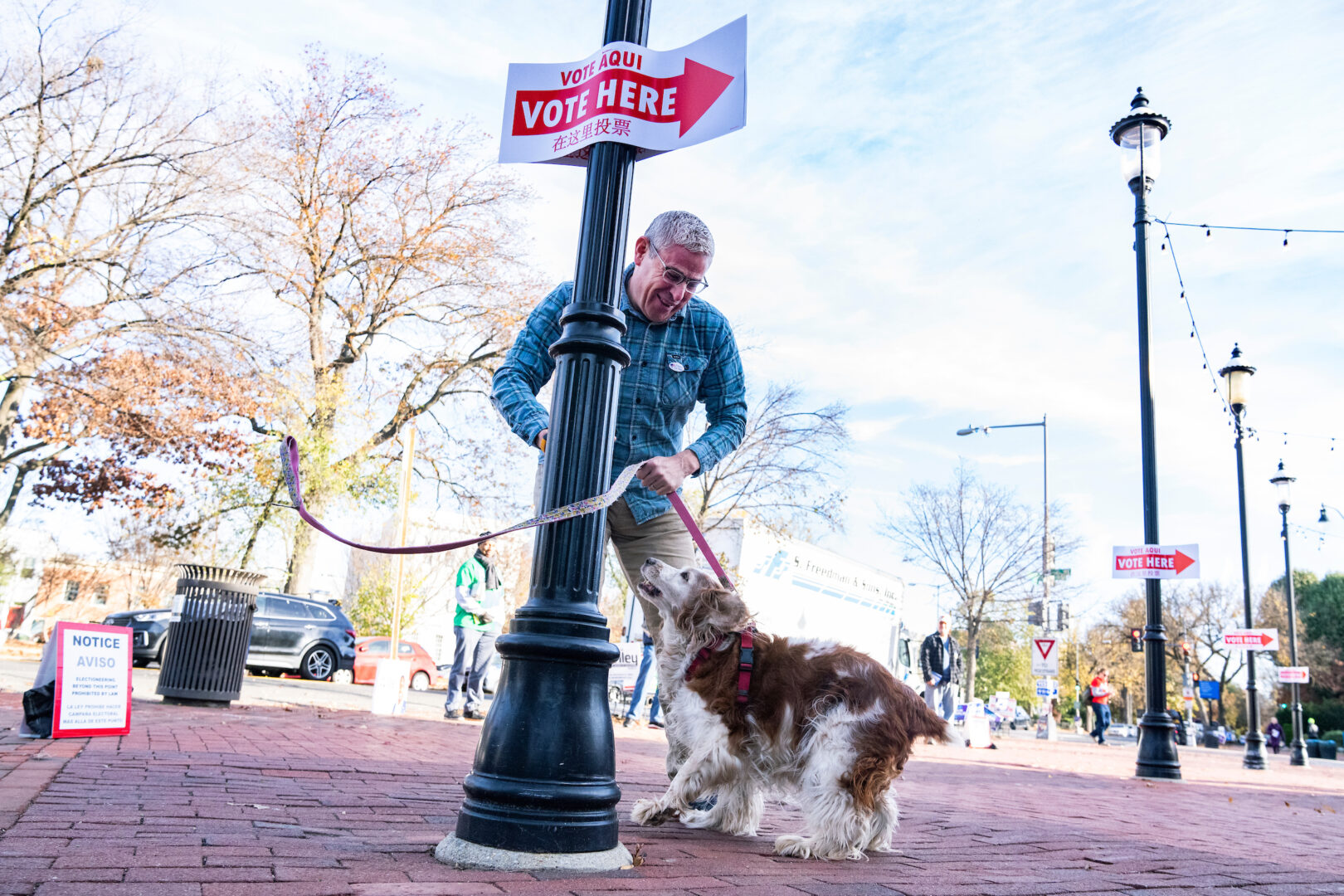 A man unties his dog after voting in D.C. in 2022. Candidates won’t win over voters with endless attack ads, Winston writes.